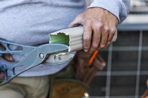 trabajador cortando canaletas de lluvia de aluminio con cizallas pesadas foto