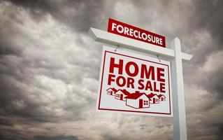 White and Red Foreclosure Home For Sale Real Estate Sign Over Cloudy Sky. photo