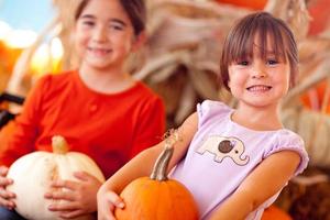 Cute Little Girls Holding Their Pumpkins At A Pumpkin Patch photo