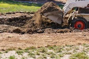 Small Bulldozer Digging In Yard For Pool Installation photo