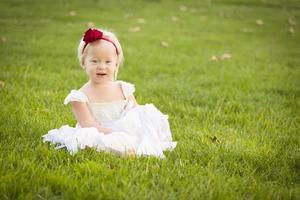 Adorable Little Girl Wearing White Dress In A Grass Field photo