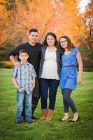 Hispanic Pregnant Family Portrait Against Fall Colored Trees photo