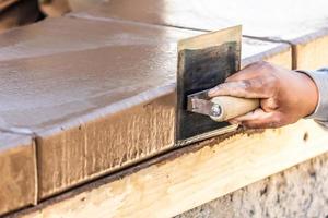 Construction Worker Using Stainless Steel Edger On Wet Cement Forming Coping Around New Pool photo