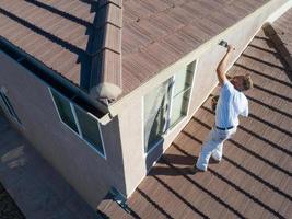 pintor profesional usando un pincel para pintar la fascia de la casa foto