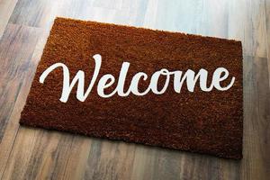 Dark Brown Welcome Mat On Wood Floor Background. photo