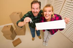 Goofy Couple Holding Keys and Blank Sign Surrounded by Boxes photo