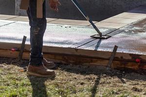 Construction Worker Smoothing Wet Cement With Long Handled Edger Tool photo