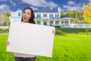 hembra de raza mixta con un cartel en blanco frente a la casa foto