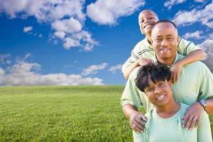 familia feliz sobre campo de hierba, nubes y cielo foto
