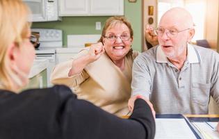 Senior Adult Couple Celebrating Over Documents in Their Home with Agent At Signing photo
