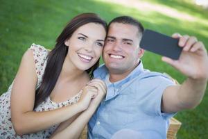 Mixed Race Couple Taking Self Portrait in Park photo