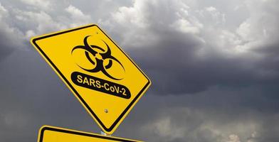 Bio-hazard Symbol With SARS-CoV-2 Coronaravirus Yellow Road Sign Against Ominous Stormy Cloudy Sky photo