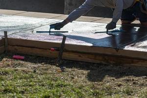 trabajador de la construcción alisando cemento húmedo con herramientas de paleta foto