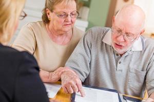 Senior Adult Couple Going Over Documents in Their Home with Agent At Signing photo