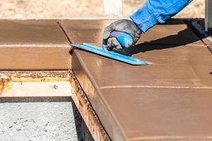 Construction Worker Using Trowel On Wet Cement Forming Coping Around New Pool photo