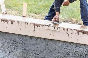 Construction Worker Using Trowel On Wet Cement Forming Coping Around New Pool photo