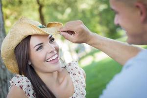 Mixed Race Romantic Couple with Cowboy Hat Flirting in Park photo