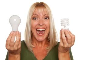 Woman Holds Energy Saving and Regular Light Bulbs photo
