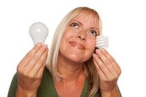 Smiling Woman Holds Energy Saving and Regular Light Bulbs photo