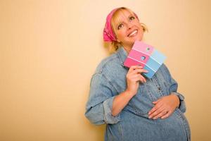 Pensive Pregnant Woman Holding Pink and Blue Paint Swatches photo