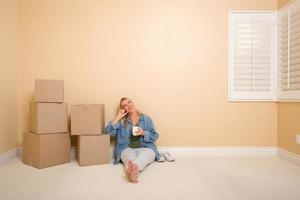 Happy Woman Relaxing Next to Boxes on Floor with Cup photo