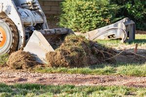 Small Bulldozer Removing Grass From Yard Preparing For Pool Installation photo