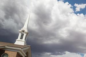 Church Steeple Tower Below Ominous Stormy Thunderstorm Clouds. photo