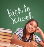 Cute Hispanic Girl Studying In Front of Back To School Written on Chalk Board photo