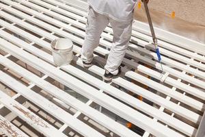 Professional Painter Rolling White Paint Onto The Top of A Home Patio Cover. photo