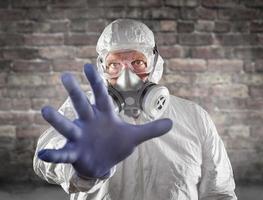 Man Wearing Hazmat Suit, Protective Gas Mask and Goggles Reaching Out With Hand photo