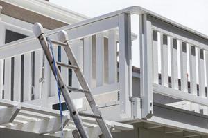 Construction Ladder and Painting Hose Leaning on House Deck photo