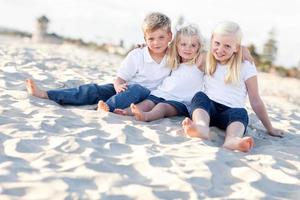 adorables hermanas y hermano divirtiéndose en la playa foto