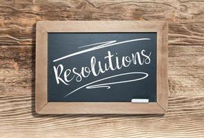 Resolutions Written on Slate Chalk Board Against Aged Wood Background photo