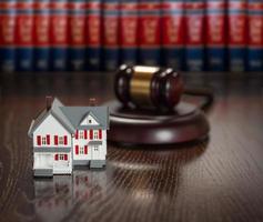 Gavel and Small Model House on Wooden Table. photo