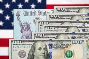 Seiscientos dólares y cheque de estímulo del irs de los estados unidos descansando sobre la bandera americana foto