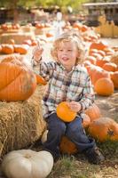 Little Boy Sitting and Holding His Pumpkin at Pumpkin Patch photo