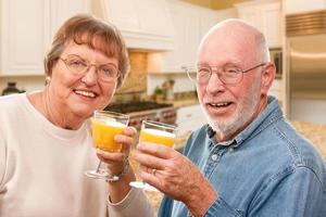 Happy Senior Couple with Glasses of Orange Juice photo