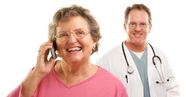 Happy Senior Woman Using Cell Phone with Male Doctor Behind photo