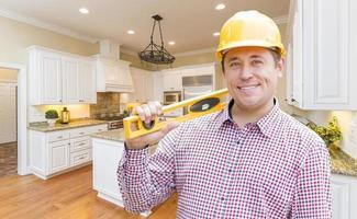 Contractor with Level Wearing Hard Hat Standing In Custom Kitchen photo