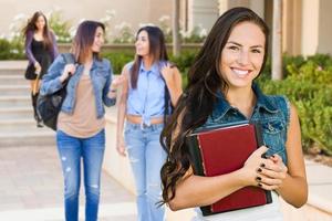 estudiante de raza mixta con libros escolares en el campus foto