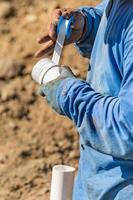 fontanero aplicando cinta de ptfe a tubería de pvc en el sitio de construcción foto