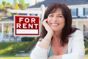 Middle Aged Woman In Front of House with For Rent Real Estate Sign In Yard photo