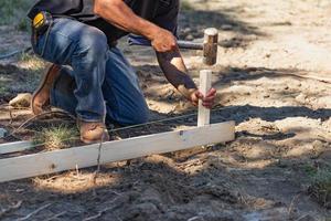 Worker Installing Stakes and Lumber Guides At Construction Site photo