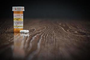 Non-Proprietary Prescription Medicine Bottle and Pills on Reflective Wooden Surface. photo