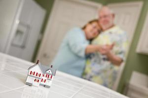 Una pareja de adultos mayores contemplando una pequeña casa modelo en el mostrador foto