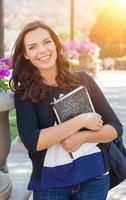 Portrait of Pretty Young Female Student Carrying Books on School Campus. photo