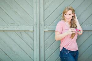 Outdoor Portrait of Young Adult Brown Eyed Woman Listening To Music with Earphones on Her Smart Phone. photo