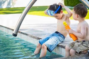 Young Mixed Race Chinese and Caucasian Brothers Wearing Swimming Goggles Playing At The Pool photo