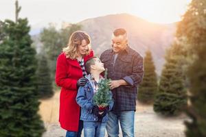 familia de raza mixta al aire libre en la granja de árboles de navidad foto