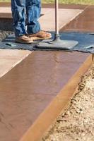 Construction Worker Applying Pressure to Texture Template On Wet Cement photo